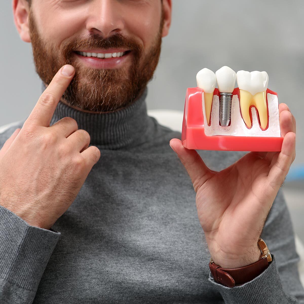 Man holding educational model of dental implant on blurred background, closeup. Space for text